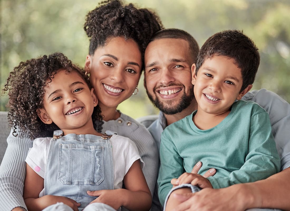 Personal Insurance - Happy Mother and Father Embrace Their Two Small Children at Home